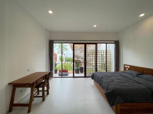 een slaapkamer met een bed en een houten tafel bij Saltera Kedungu in Tanah Lot
