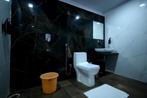 a black bathroom with a toilet and a sink at The Van Bagh Ranthambore in Sawāi Mādhopur