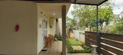 een veranda van een huis met stoelen en een parasol bij Hansel Homestay in Batu