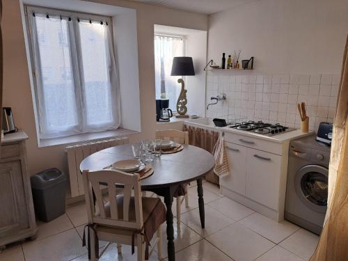 eine Küche mit einem Tisch mit Stühlen und einem Herd in der Unterkunft La Tanière in Bains-les-Bains