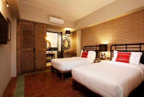 a bedroom with two beds and a brick wall at Baan Chart in Bangkok