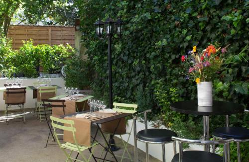 a patio with tables and chairs and a hedge at Hotel De Paris Jaligny in Jaligny