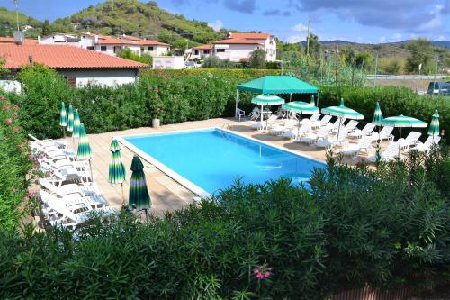 a swimming pool with lawn chairs and umbrellas at Pozzo al Moro Village in Marina di Campo