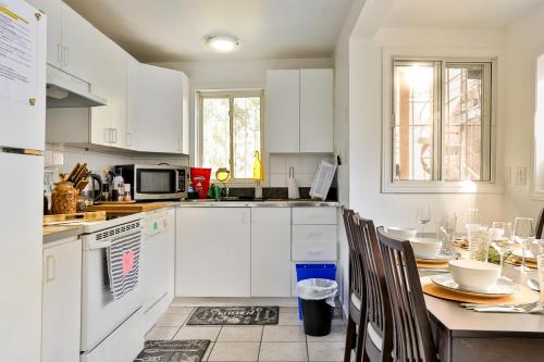 a kitchen with white cabinets and a table with chairs at 250 METERS to METRO BERRI UQAM - Spacious fully equipped APARTMENTS - 1 FREE PARKING per unit - in-unit Washer & Dryer - fully stocked KITCHEN - WORKSPACE PROVIDED - FAST WIFI - 5 minute walk to the FAMOUS ST CATHERINE & ST DENIS STREET in Montréal