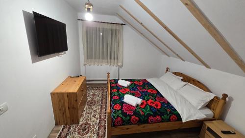 a bedroom with a bed and a tv on the wall at La Murmur de Padure in Bălnaca
