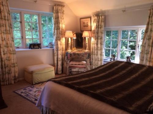 a bedroom with a bed and a room with windows at Bridge Cottage in Midhurst