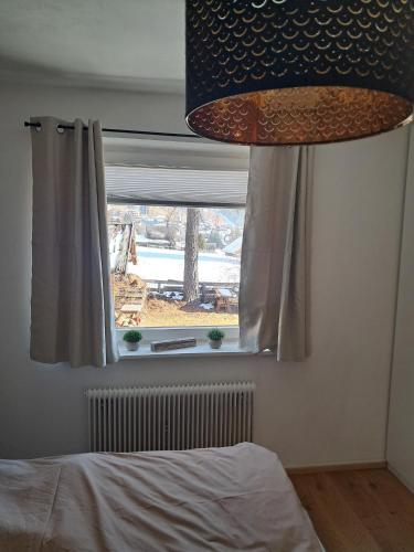 ein Schlafzimmer mit einem Fenster mit einem Bett und einer Lampe in der Unterkunft Das Litzldorf in Sankt Michael im Lungau