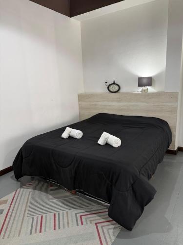 ein Schlafzimmer mit einem schwarzen Bett mit zwei Handtüchern darauf in der Unterkunft EzeApart in Ezeiza
