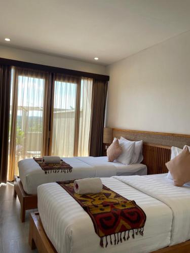 two beds in a hotel room with windows at SVARGA RENJANA ViLLA in Lombok