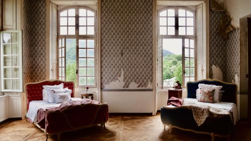 een slaapkamer met twee bedden en twee ramen bij Chateau de Gudanes in Château-Verdun