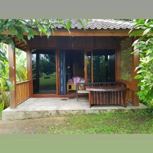 een houten paviljoen met een bank op een patio bij waroeng bangket in Mantang
