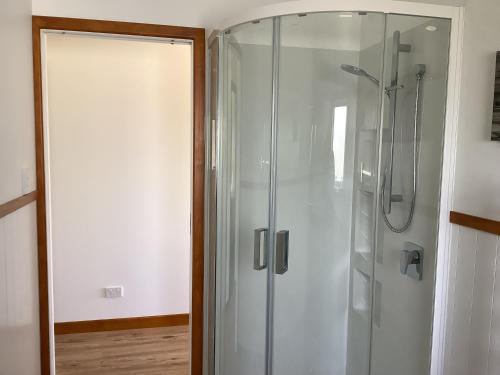 a shower with a glass door next to a room at Ocean Breeze Holiday Home in Riverton