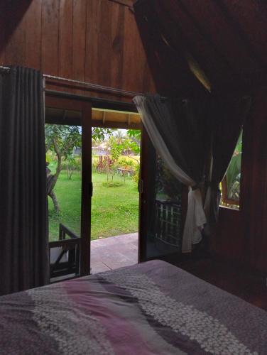 een slaapkamer met een bed en een deur naar een tuin bij waroeng bangket in Mantang