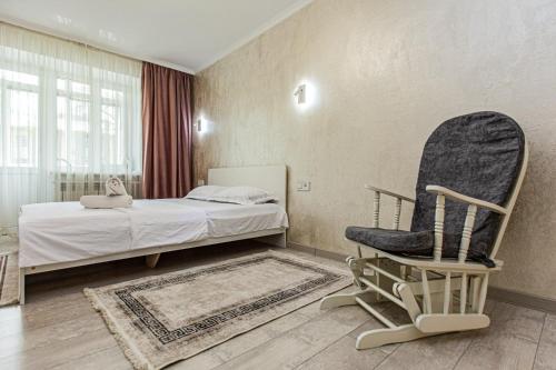 a bedroom with a bed and a rocking chair at Гоголя 117 in Almaty
