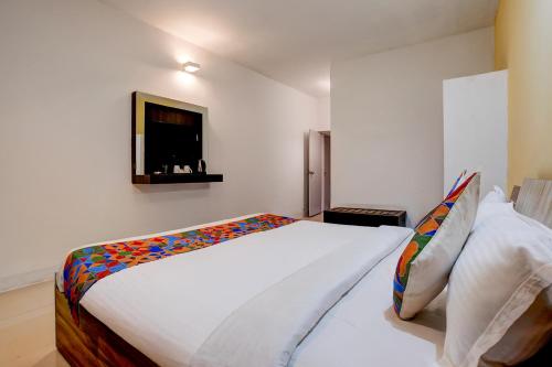 een slaapkamer met een groot bed en een tv aan de muur bij FabHotel Bay Breeze in Morjim