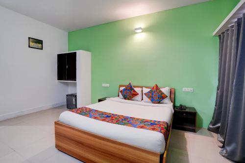 een slaapkamer met een bed en een groene muur bij FabHotel Bay Breeze in Morjim