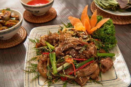 a plate of food with meat and vegetables on a table at Hotel Thi Hoa Bai Dinh in Ninh Binh