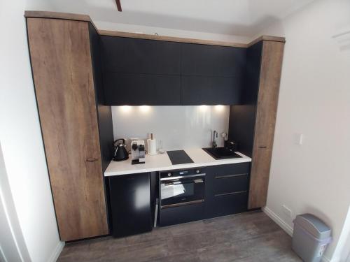 a small kitchen with black cabinets and white counters at Elks Nook Retreat - Luxurious Escape - Perth Hills in Byford