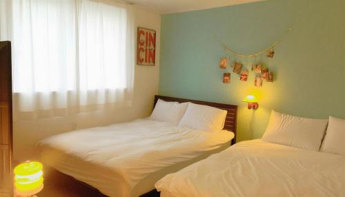 twee bedden in een kleine kamer met een raam bij The Cozy Oven in Busan