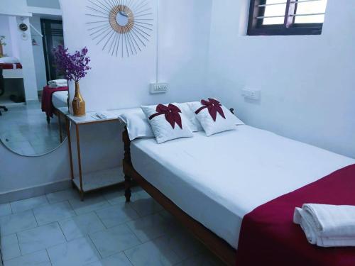 a bedroom with a bed with white sheets and a mirror at Family Vacation Rental Villa in Alappuzha - LAYANILA in Alleppey