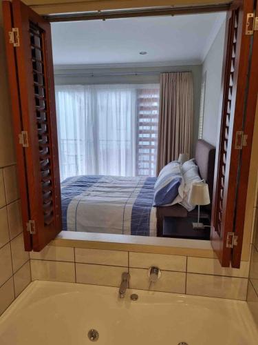 a bathroom with a large mirror over a bath tub at Villa 46 in Pauanui