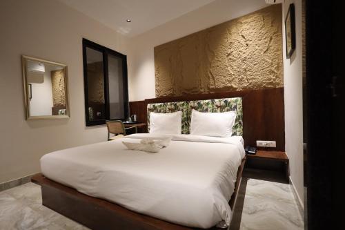 een slaapkamer met een groot wit bed en een bureau bij Hotel Destin in Gwalior