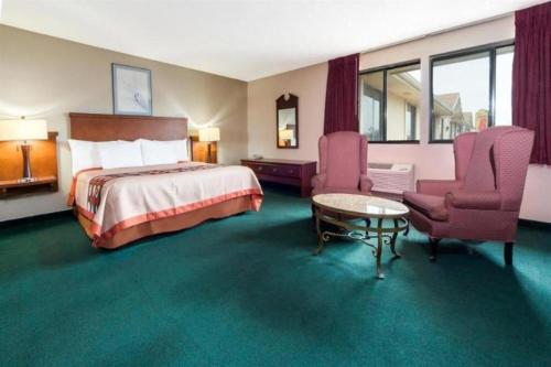 a hotel room with a bed and two chairs at Quality Inn & Suites in Bridgeton