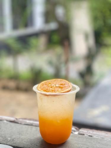 a cup of orange juice sitting on a table at ใจกลม โฮมคาเฟ่ in Ban Hua Phrong