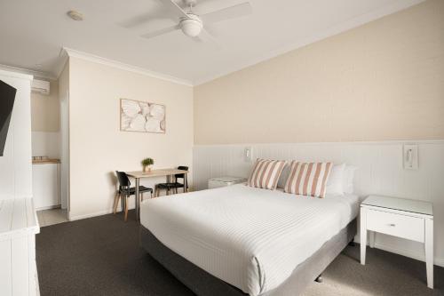 a bedroom with a bed and a desk and a table at Catalina Motel Lake Macquarie in Toronto