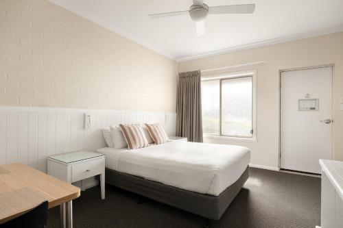 a white bedroom with a bed and a window at Catalina Motel Lake Macquarie in Toronto