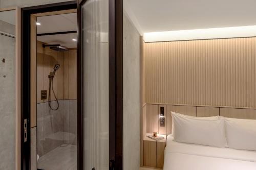 ein Schlafzimmer mit einer Dusche und einem weißen Bett in der Unterkunft The Cara Hotel in Kota Kinabalu
