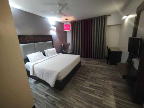 une chambre d'hôtel avec un lit et une télévision dans l'établissement POP 84200K M K Elegance Inn, à Coimbatore (Peelamedu)