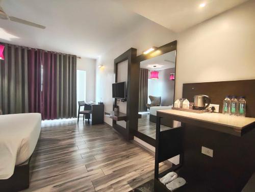 une chambre d'hôtel avec un lit et un miroir dans l'établissement POP 84200K M K Elegance Inn, à Coimbatore (Peelamedu)