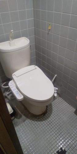 a bathroom with a white toilet in a stall at raibrasil guest house in Sanuki