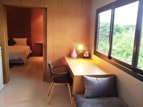 Cette chambre comprend un bureau, un lit et une fenêtre. dans l'établissement Klim Hotel, à Buriram