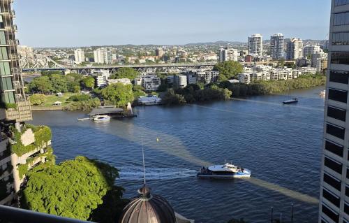 a boat traveling down a river in a city at Lux 18th floor 2br 2bath, River view, Pool, Spa, Sauna, Gym, Wifi, in Brisbane