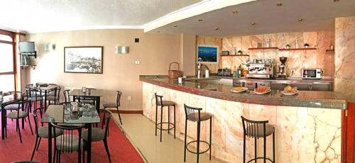 カストロ・ウルディアレスにあるHotel La Rondaのテーブルとキッチン付きのバーのあるレストランを提供しています。