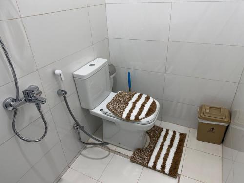 un bagno con un water con un tappeto marrone e bianco di Sky5 Apartment a Sharīyah