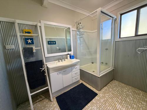 a bathroom with a sink and a shower and a tub at Lakeview Cottage in Forster