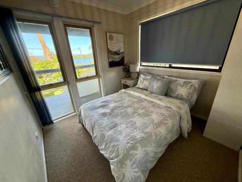 a bedroom with a bed and a large window at Lakeview Cottage in Forster