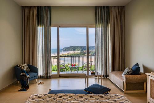 a bedroom with a bed and a view of the ocean at Araqila in Vengurla