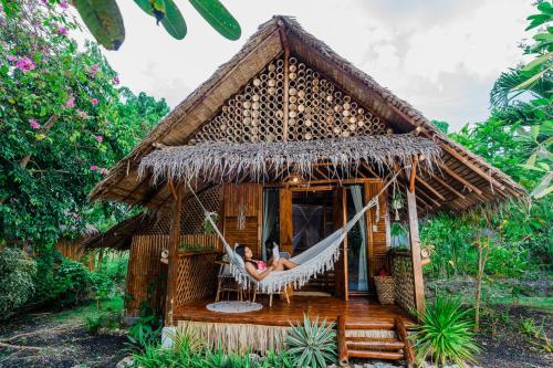 a woman sitting in a hammock in a thatch hut at Tongo Hill Cottages in Moalboal