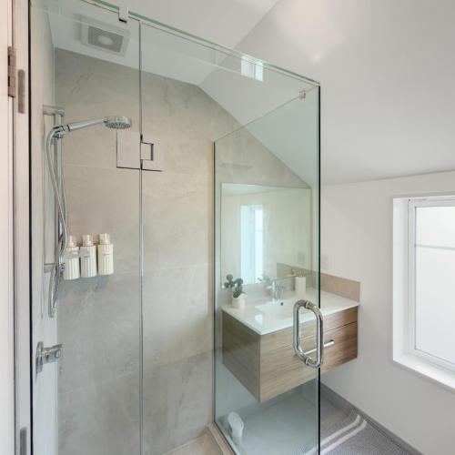 a glass shower in a bathroom with a sink at Modern Heritage 2BR Home in Christchurch