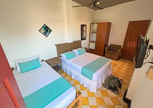 een hotelkamer met twee bedden en een televisie bij Hotel Casa de Sarah in Santa Marta
