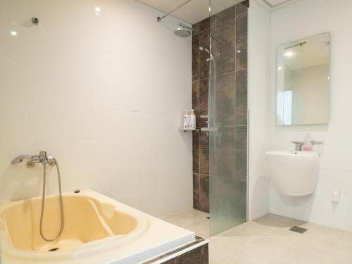 a bathroom with a tub and a shower and a sink at Hallasan Resort in Sanch'ŏndan