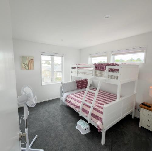 a bedroom with two bunk beds and a fan at Modern Heritage 2BR Home in Christchurch
