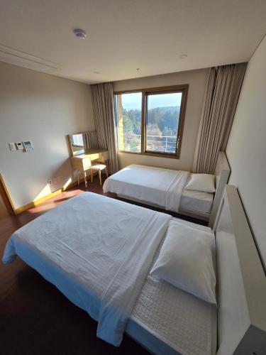 a hotel room with two beds and a window at Hallasan Resort in Sanch'ŏndan