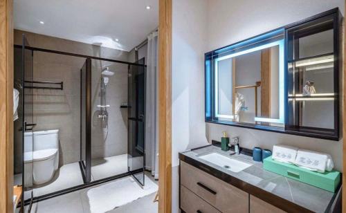 a bathroom with a shower and a sink and a mirror at Nanshe Nan Inn Dali in Dali Airport