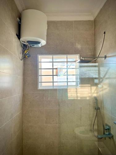 een badkamer met een douche, een raam en een wastafel bij home in Nungwi