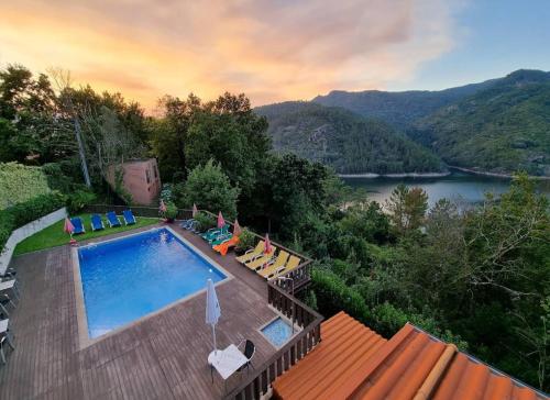 a swimming pool with chairs and a view of a river at Casa Encosta do Gerês-Ferias no Gerês in Vieira do Minho